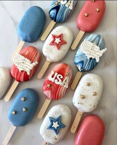 an assortment of decorated ice cream pops on a white counter top with stars and stripes