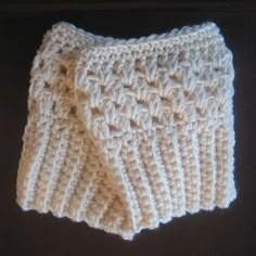 a close up of a crocheted dishcloth on a black surface with white yarn