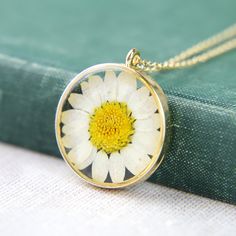 "A delightful and summery real, dried and pressed flower with the classic white petals and yellow centre, encased in resin and with a gold plated setting, all hung from a gold plated fine chain. The pendant measures 3cm (1.2\") high and across. Choose a chain length tailored to you  **Gifts And Treating Yourself** Each item is individually packaged in a 'The Pretty Ditty' gift box or reuseable cotton gift bag. All packages are shipped in a recycable cardboard box. We do not include any price rec Dainty White Round Flower Necklace, Nature-inspired White Birth Flower Necklace, White Flower Charm Necklace, White Flower Pendant Necklace With Birth Flower, White Dainty Flower Necklace, Dainty White Birth Flower Necklace, Delicate White Birth Flower Necklace, White Flower Pendant Necklace With Pressed Flowers, Vintage White Jewelry With Pressed Flowers