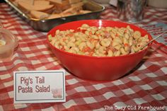 a red bowl filled with pasta sitting on top of a checkered tablecloth covered table