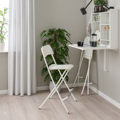 a white folding chair next to a desk with a potted plant on top of it