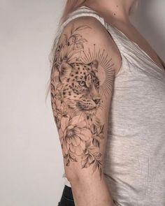 a woman's arm with a leopard and flowers tattoo on the left side of her arm