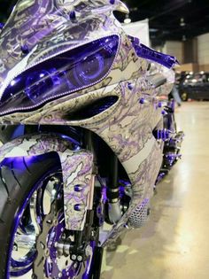 the motorcycle is decorated with purple and silver designs on it's body, as well as its hood