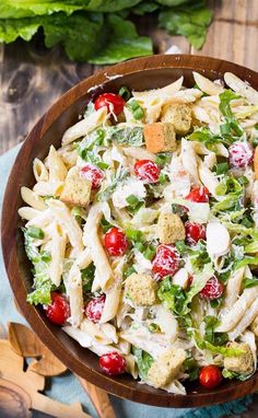 a wooden bowl filled with pasta salad on top of a table