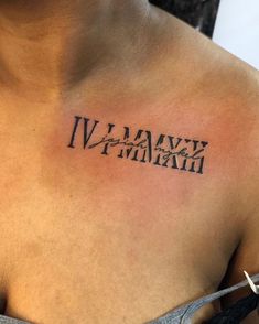 a woman's chest with roman numerals tattooed on her upper arm and shoulder