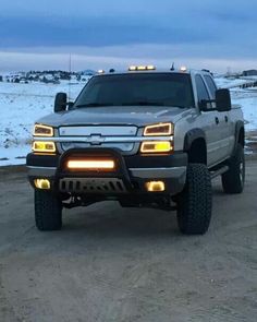 a silver truck parked on top of a snow covered road in the middle of winter