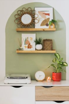 two wooden shelves with plants and pictures on them in a living room next to a white dresser