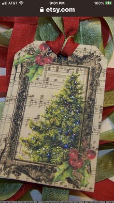 a christmas card with a tree on it and red ribbon around the edges, hanging from a green bow