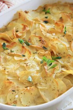 a casserole dish with potato chips and herbs in it on a white plate