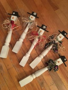 four white candles with bows and snowmen on them sitting on a wooden floor next to each other