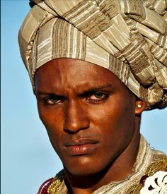 a man in a turban looks at the camera with an intense look on his face