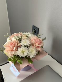 a bouquet of flowers sitting on top of a white table next to a light switch