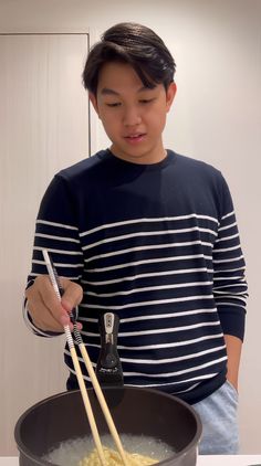 a man is stirring some food with chopsticks