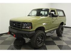 a green pick up truck is parked on a checkered floor