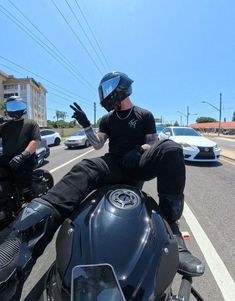 two motorcyclists are riding down the street on their bikes and one is waving