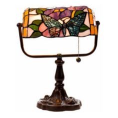 a stained glass table lamp with a butterfly design on the top and bottom, sitting on a stand