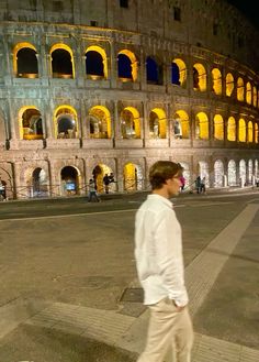 a man is walking down the street in front of an old building at night time