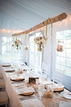 a long table set with place settings and flowers on it for an outdoor wedding reception