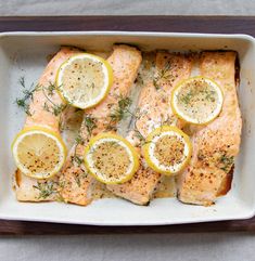 salmon with lemons and herbs in a baking dish