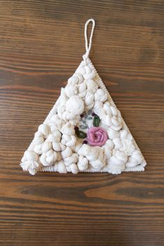 a white ornament with flowers on it sitting on a wooden table next to a piece of string