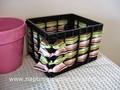 a pink flower pot sitting next to a black container filled with colorful striped napkins