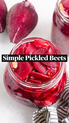 two jars filled with pickled beets on top of a white tablecloth and striped napkin