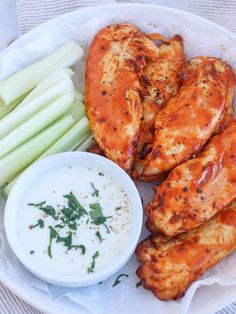 a plate with chicken wings, celery and dip