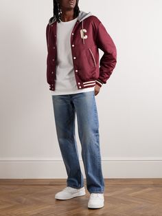 CELINE HOMME's varsity jacket is modelled after collegiate styles, from the classic striped trims to the terry logos at the chest and across the back. Lightly padded for warmth, it's made from glossy burgundy nylon and has a soft jersey hood that furthers the sporty feel.