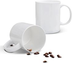 two coffee mugs with beans spilling out of them