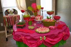 a pink table topped with lots of desserts and candies on top of it