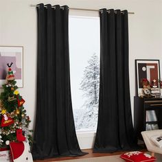 a living room with a christmas tree in the corner and black drapes on the window