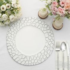 a white table setting with flowers and silverware