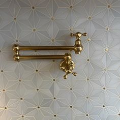 two golden handles on the wall in a room with white and gold geometric tile pattern