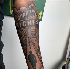 a man's arm with a road to richies sign tattooed on the side