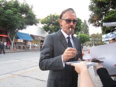 a man in a suit and tie is being interviewed by someone on the side of the road