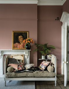 a living room with pink walls and a white couch in front of a painting on the wall