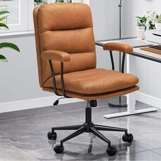 a brown office chair sitting in front of a computer desk