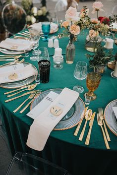 a table set with place settings and gold utensils for an elegant dinner party