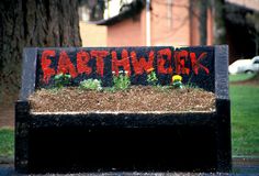 a sign that says earthwork with flowers in the center and grass growing out of it