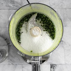 a blender filled with green and white ingredients on top of a marble countertop