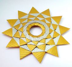 an origami sunflower made out of yellow and white paper with a circular hole in the middle