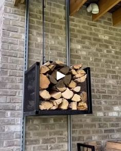 a firewood rack hanging from the side of a brick wall with logs stacked on it