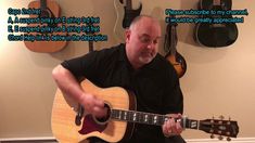 a man playing an acoustic guitar in front of guitars