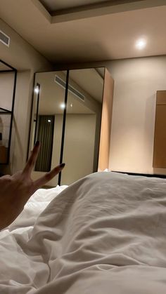 a person reaching up to catch a pillow on a bed in a room with mirrored walls