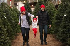 a man, woman and child are walking through christmas trees