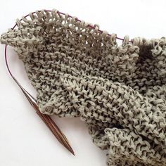 a pair of knitting needles next to a knitted scarf