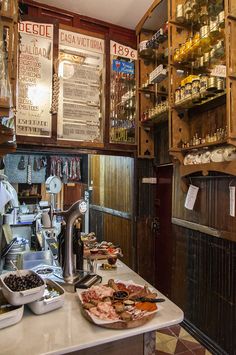 a counter with some food on it in a room filled with wooden shelves and signs