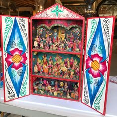 an elaborately painted bookcase with figurines on it's front and sides