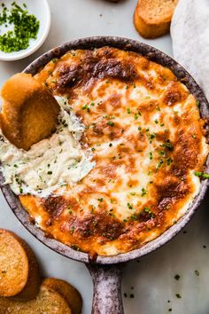 a baked dish with cheese and sauce in it next to some crackers on the side