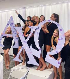 a group of women standing next to each other holding up letters